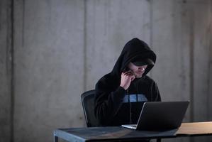 hacker talentoso que usa una computadora portátil mientras trabaja en una oficina oscura foto