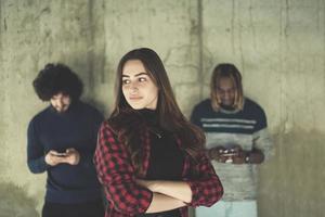 equipo de negocios multiétnico casual usando teléfonos móviles frente a un muro de hormigón foto