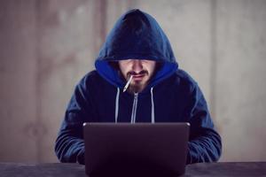 young hacker using laptop computer while working in dark office photo