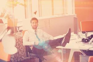 relaxed young businessman first at workplace at early morning photo