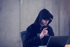 talented hacker using laptop computer while working in dark office photo