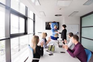 boss dresed as bear having fun with business people in trendy office photo