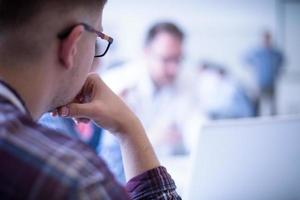 Business man writing notes while working on laptop photo