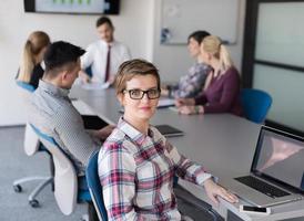 portrait of young business woman at office with team on meeting in background photo