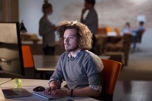 hombre trabajando en una computadora en una oficina oscura foto