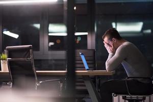 man working on laptop in dark office photo