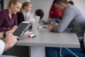 Cerca de las manos de un hombre de negocios usando una tableta en una reunión foto