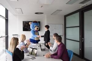 boss dresed as bear having fun with business people in trendy office photo