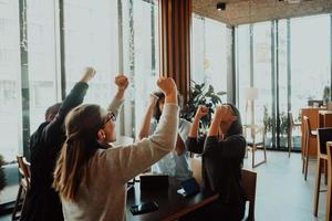 un grupo de empresarios celebra con las manos en alto foto