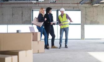 architect showing house design plans to a young couple photo