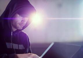 young talented hacker using laptop computer while working in dark office photo