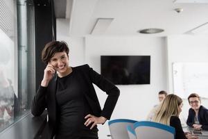 Elegant Woman Using Mobile Phone by window in office building photo