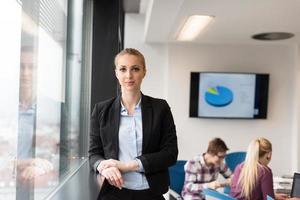 portrait of young business woman at office with team on meeting in background photo