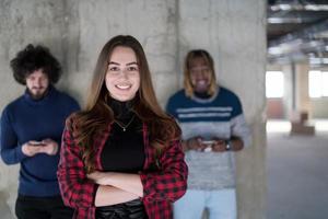 equipo de negocios multiétnico casual usando teléfonos móviles frente a un muro de hormigón foto