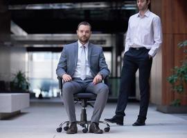 business man sitting in office chair, people group  passing by photo