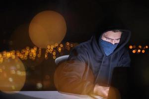 hacker using laptop computer while working in dark office photo