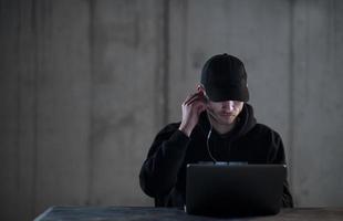 talented hacker using laptop computer while working in dark office photo