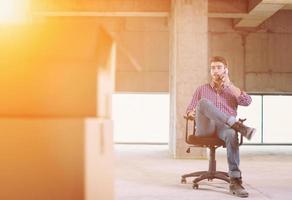 young casual businessman using mobile phone on construction site photo