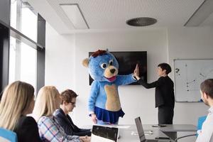 boss dresed as bear having fun with business people in trendy office photo