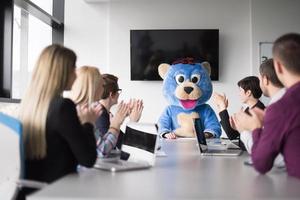 jefe vestido como oso divirtiéndose con gente de negocios en una oficina de moda foto