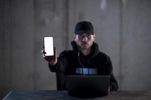 criminal hacker using laptop computer while working in dark office photo