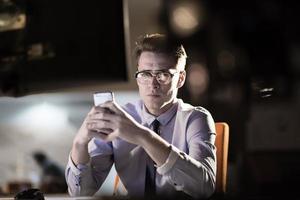 man using mobile phone in dark office photo