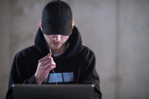 talented hacker using laptop computer while working in dark office photo