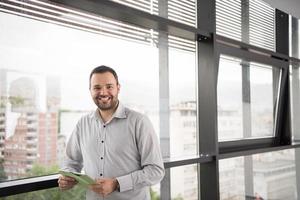 hombre de negocios que usa una tableta en un edificio de oficinas junto a la ventana foto