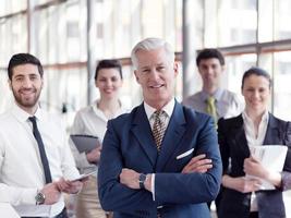 portrait of senior businessman as leader  with staff in background photo