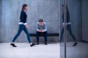 businessman using mobile phone while sitting on the bench photo