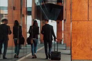 Business man and business woman talking and holding luggage traveling on a business trip, carrying fresh coffee in their hands.Business concept photo