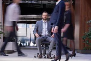 business man sitting in office chair, people group  passing by photo