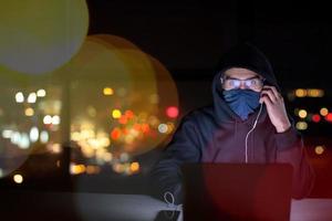 hacker using laptop computer while working in dark office photo