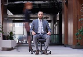 business man sitting in office chair, people group  passing by photo