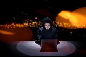 hacker using laptop computer while working in dark office photo