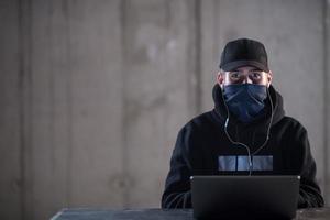 talented hacker using laptop computer while working in dark office photo