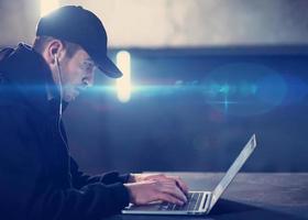 young talented hacker using laptop computer while working in dark office photo