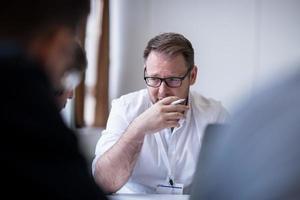 Business man writing notes while working on laptop photo