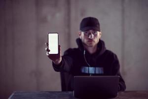 criminal hacker using laptop computer while working in dark office photo