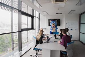 jefe vestido como oso divirtiéndose con gente de negocios en una oficina de moda foto