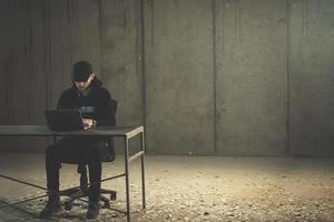 talented hacker using laptop computer while working in dark office photo