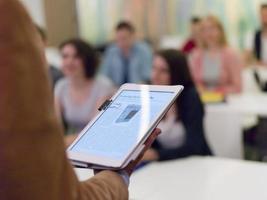 Closeup  teacher hands and tablet while teaching studens in modern classroom photo