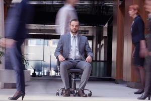 business man sitting in office chair, people group  passing by photo