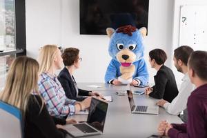 boss dresed as bear having fun with business people in trendy office photo