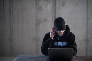 talented hacker using laptop computer while working in dark office photo
