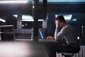 man working on laptop in dark office photo