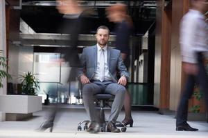 business man sitting in office chair, people group  passing by photo