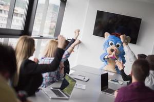 boss dresed as bear having fun with business people in trendy office photo