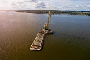 Cleaning the river bottom with a crane and a barge top view photo