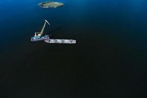 Cleaning the river bottom with a crane and a barge top view photo